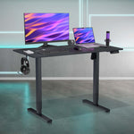 Height-adjustable black desk with computer setup.