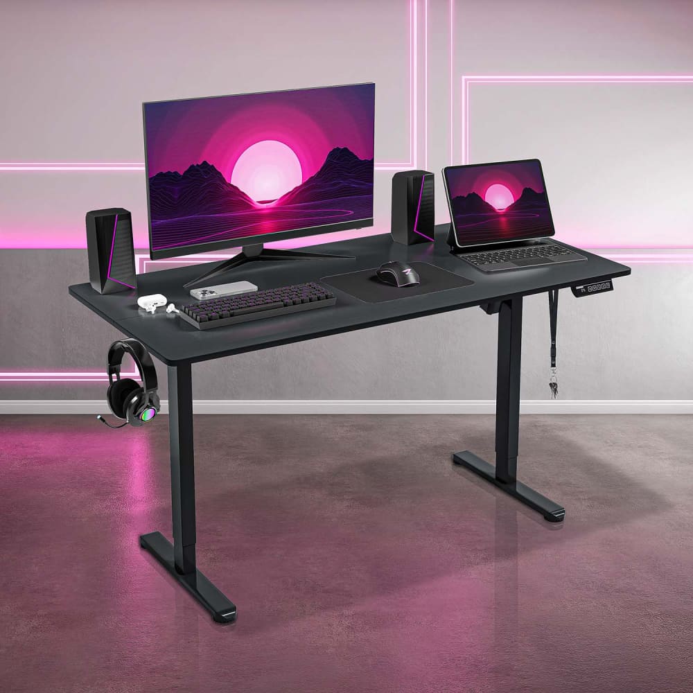 Black adjustable gaming desk with electronics.