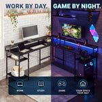 A split-screen promotional image showing a black metal gaming desk in two settings: a minimalist home office setup on the left labeled 'WORK BY DAY' and a dark gaming room on the right labeled 'GAME BY NIGHT'. The desk features a desktop surface, open shelving, and a lower storage shelf with a visible PC tower. 