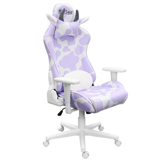 A girl gaming chair for cute purple gaming setups. The purple cow gaming chair by techni sport shown against a white background at an angle. This cute gaming chair has a  reversible lumbar pillow with lavender and white print on one side and fluffy white material on the front . It features a white base, wheels and hardware. Includes a headrest with grey brown horns and cute ears with a fluffy white lining The materials used are velvet for the ultimate softness.