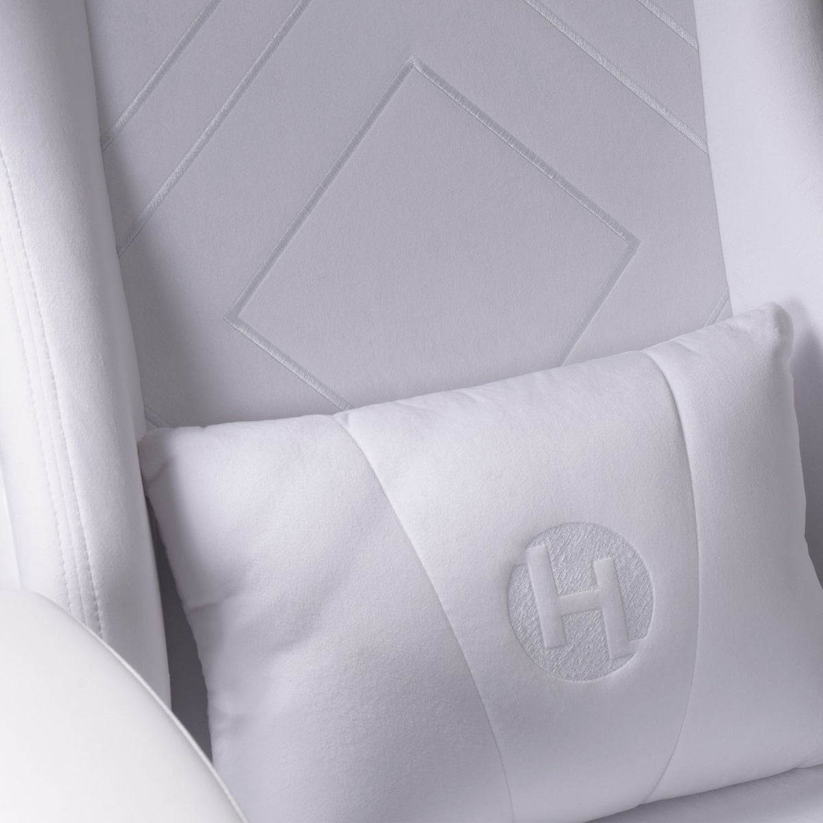 Close-up of a white quilted pillow with a geometric pattern on a matching background 