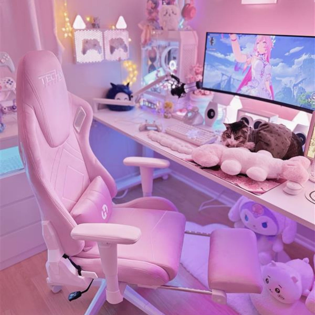 Pink gaming chair in a a pink gaming setup with a desk, computer, and plush toys.